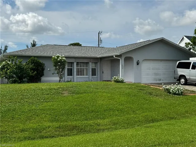 Ranch-style home with a garage and a front lawn