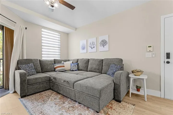 Living area with baseboards, ceiling fan, light wood finished floors, and a healthy amount of sunlight