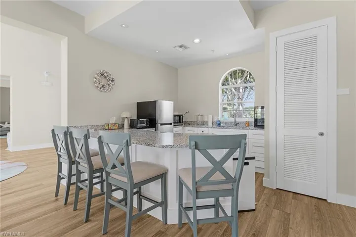 Kitchen with a breakfast bar area, visible vents, light wood-style flooring, freestanding refrigerator, and a peninsula
