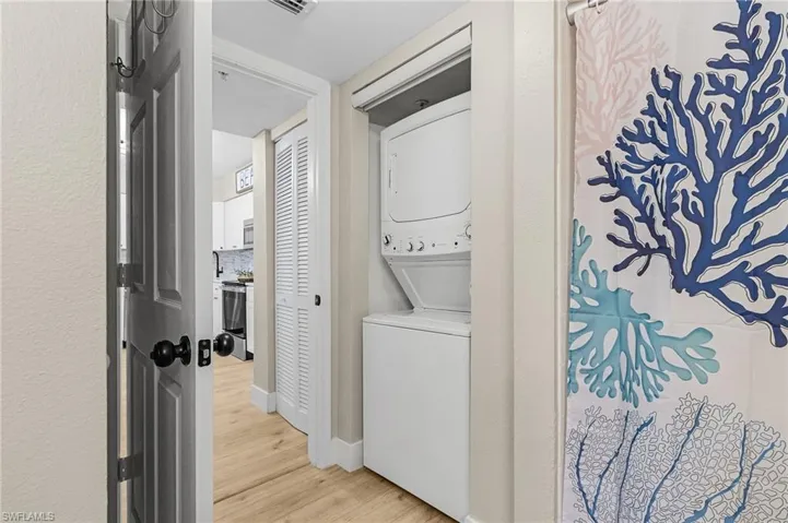 Laundry area featuring light wood-style floors, laundry area, and stacked washer and clothes dryer