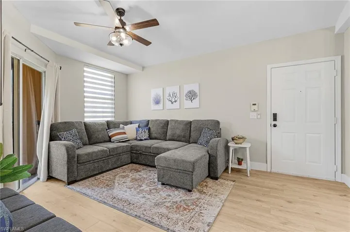 Living room with light wood finished floors, ceiling fan, and baseboards
