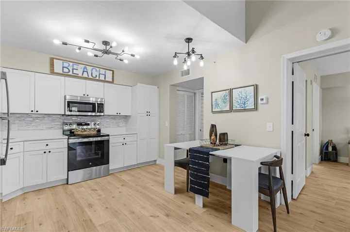 Kitchen with stainless steel appliances, light countertops, decorative backsplash, and light wood finished floors