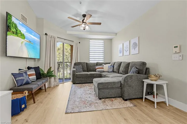 Living area featuring a ceiling fan, baseboards, visible vents, and wood finished floors