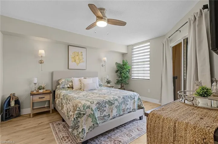 Bedroom with a ceiling fan, baseboards, a textured ceiling, and light wood finished floors
