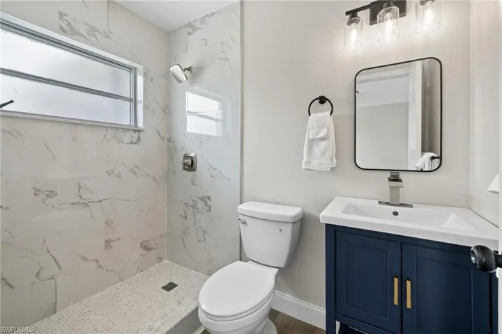 Bathroom with tiled shower, toilet, and vanity