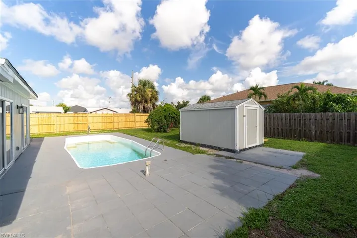 View of pool with a lawn, a shed, and a patio area