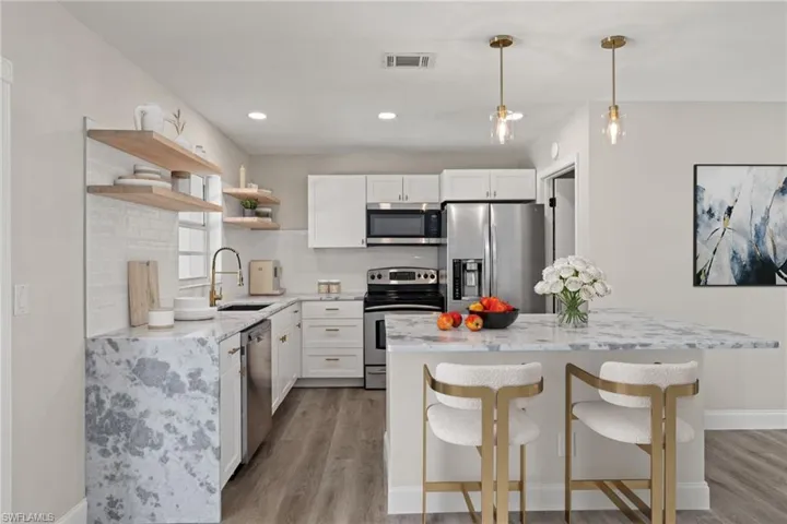 Kitchen with sink, light wood-type flooring, stainless steel appliances, and white cabinets