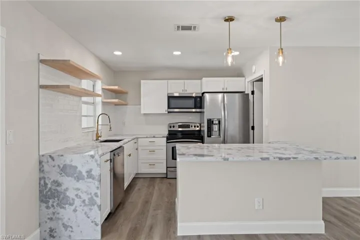 Kitchen featuring appliances with stainless steel finishes, light hardwood / wood-style flooring, white cabinets, and sink
