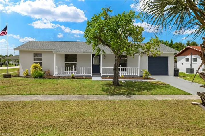 Ranch-style home featuring covered porch, a garage, central AC, and a front yard