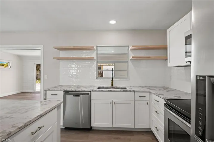 Kitchen featuring appliances with stainless steel finishes, dark hardwood / wood-style flooring, decorative backsplash, and plenty of natural light