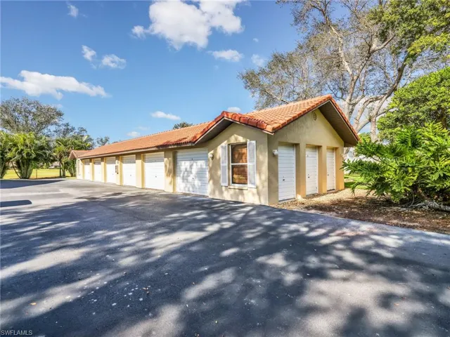 View of home's exterior with community garages, stucco siding, and a tile roof