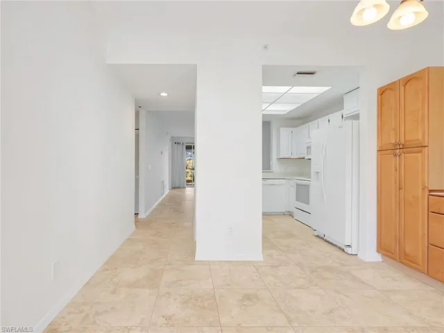 Kitchen featuring white appliances, light countertops, light tile patterned floors, light brown cabinets, and white cabinetry