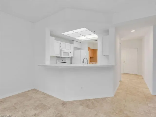 Kitchen featuring white cabinets, light countertops, white appliances, and a peninsula