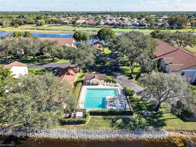 Aerial perspective of suburban area featuring a nearby body of water and a pool area