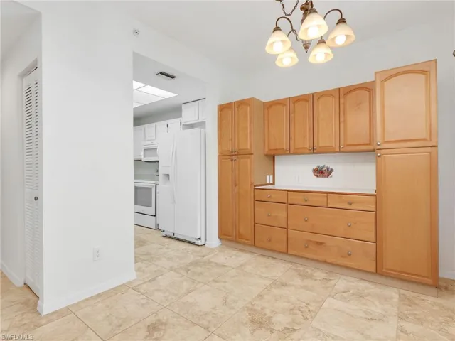 Kitchen featuring white appliances, pendant lighting, a chandelier, backsplash, and tile counters