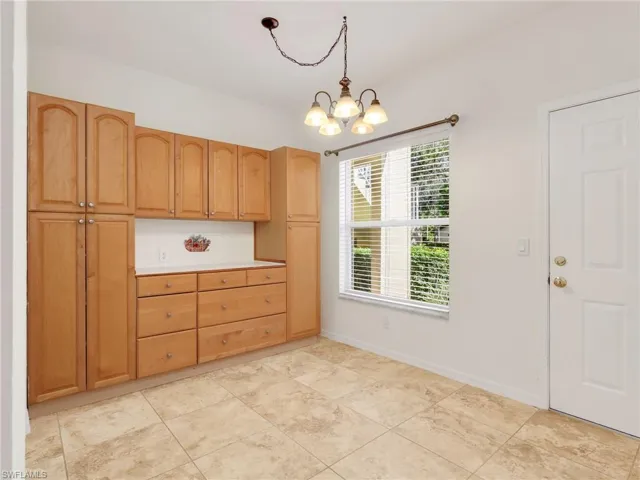 Kitchen featuring hanging light fixtures, light countertops, backsplash, and a chandelier