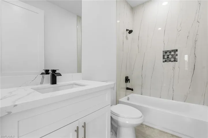 Full bathroom with tiled shower / bath, vanity, toilet, and tile patterned flooring