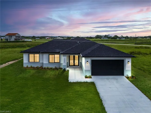 Ranch-style house featuring a garage and a yard