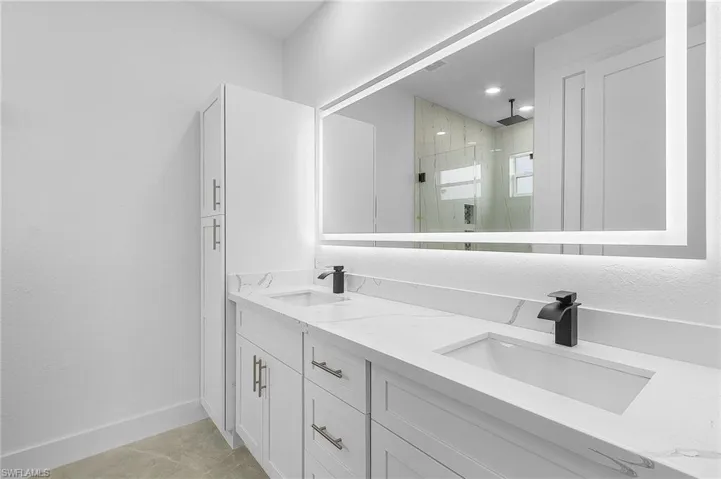 Bathroom with vanity, a shower with shower door, and tile patterned floors