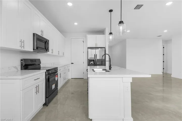 Kitchen featuring black appliances, pendant lighting, an island with sink, sink, and white cabinetry