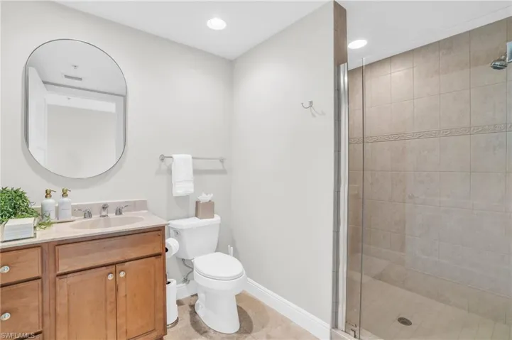 Bathroom with vanity, a shower with door, tile patterned flooring, and toilet