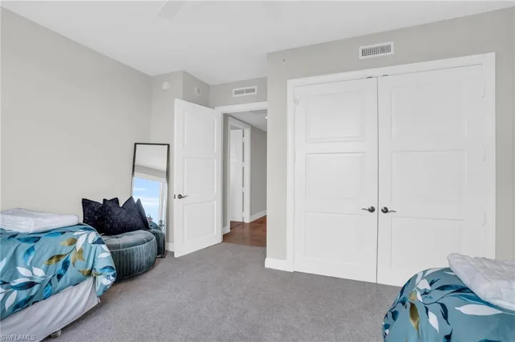 Carpeted bedroom with ceiling fan and a closet