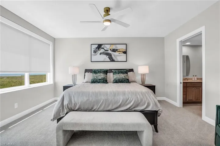 Carpeted bedroom featuring ceiling fan and connected bathroom
