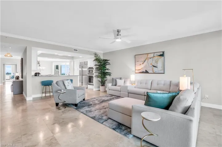 Living room with ornamental molding, light tile patterned floors, and ceiling fan