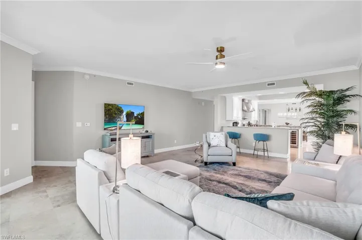Living room featuring crown molding, ceiling fan, and light tile patterned floors