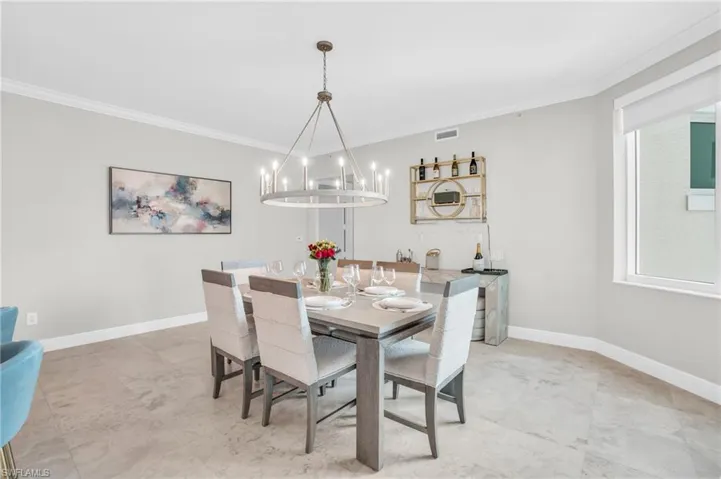 Dining space featuring an inviting chandelier, crown molding, and light tile patterned flooring
