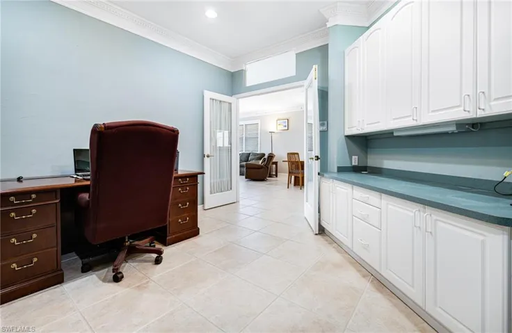 Tiled office space featuring built in desk and crown molding