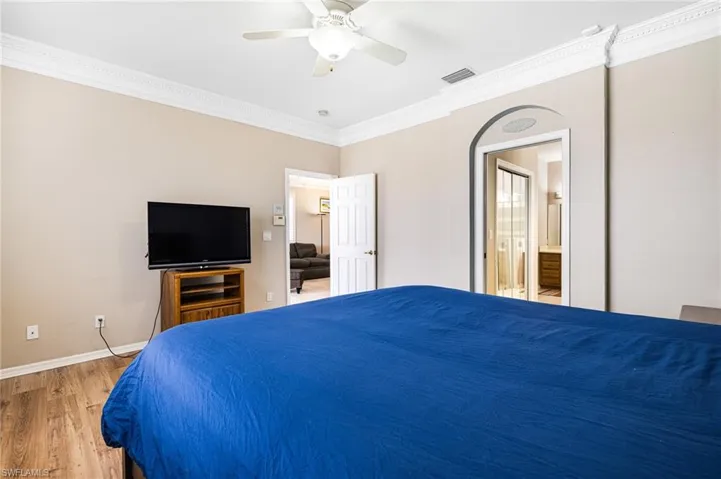 Bedroom with ceiling fan, ornamental molding, ensuite bath, and hardwood / wood-style floors