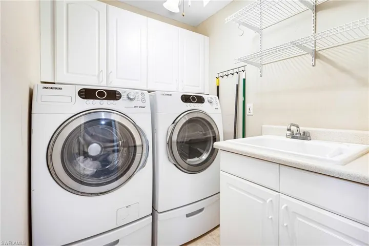 Laundry area featuring cabinets, sink, and washing machine and clothes dryer
