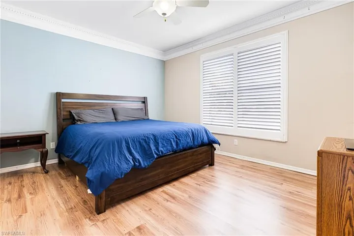 Bedroom featuring ornamental molding, hardwood / wood-style flooring, and ceiling fan