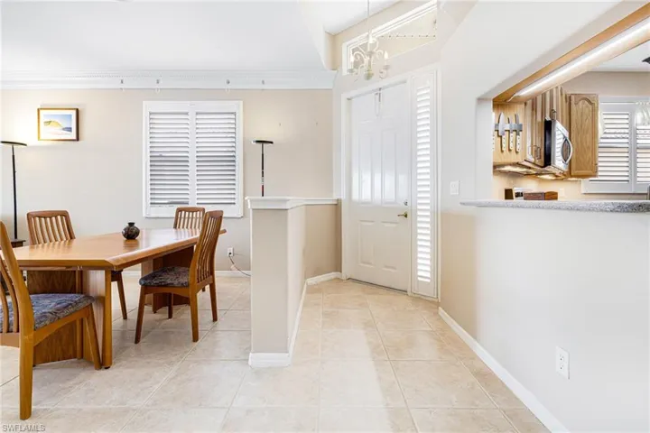 Tiled dining space featuring crown molding and a chandelier
