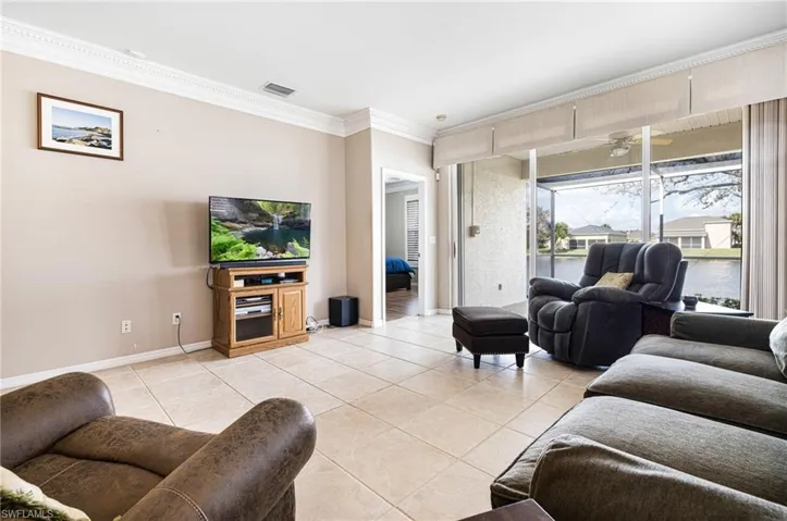 Living room featuring crown molding, light tile patterned floors, and ceiling fan