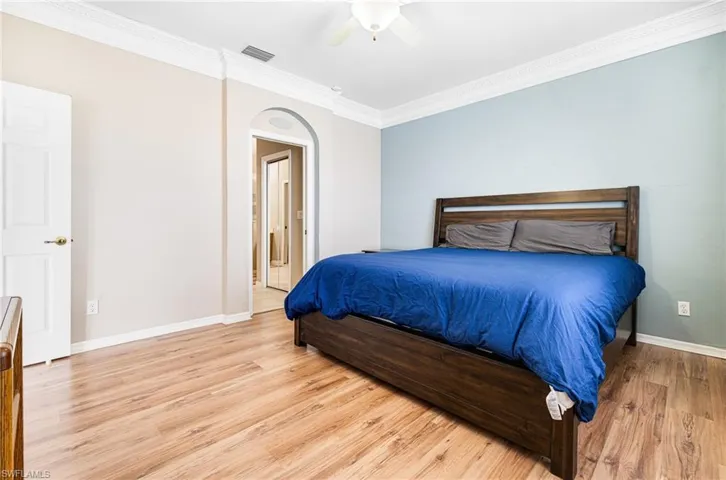 Bedroom featuring light hardwood / wood-style flooring, crown molding, and ceiling fan