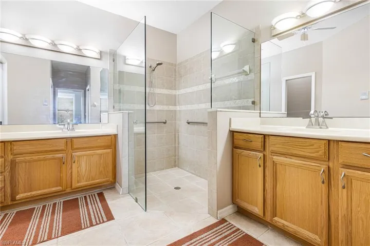 Bathroom featuring vanity, a shower with shower door, tile patterned floors, and ceiling fan