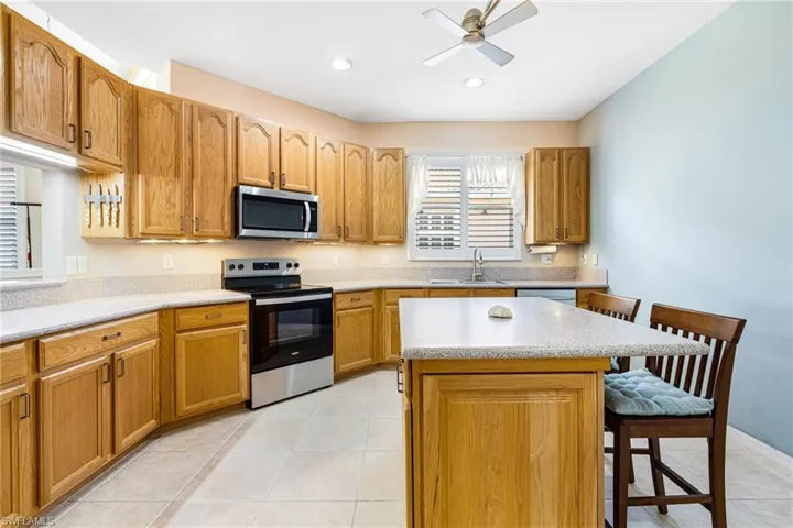 Kitchen featuring sink, a kitchen island, a breakfast bar, stainless steel appliances, and light tile patterned floors