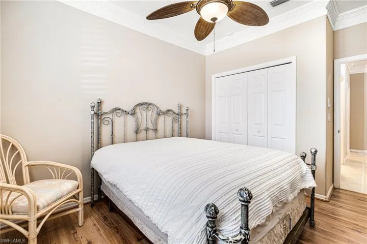 Bedroom with a closet, ceiling fan, ornamental molding, and hardwood / wood-style floors