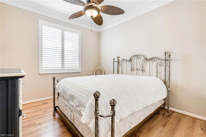Bedroom featuring ceiling fan, crown molding, and wood-type flooring