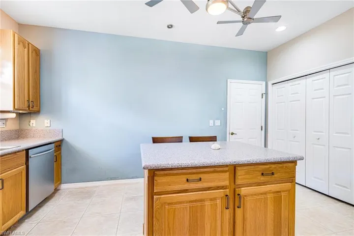 Kitchen with stainless steel dishwasher, light tile patterned floors, and ceiling fan