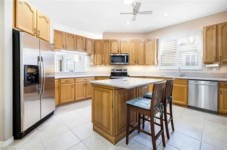 Kitchen with appliances with stainless steel finishes, a kitchen bar, light tile patterned flooring, sink, and a center island