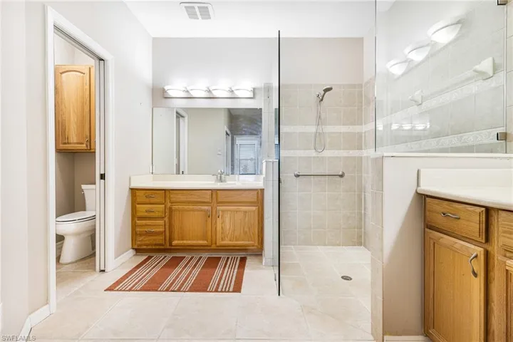 Bathroom with toilet, vanity, a tile shower, and tile patterned floors