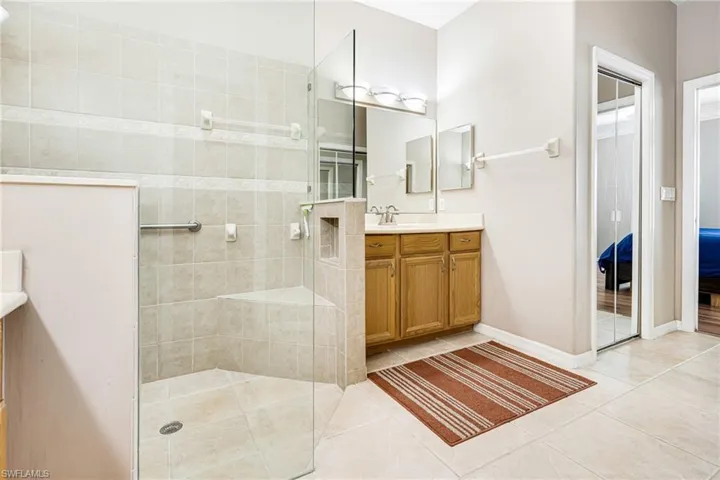 Bathroom featuring vanity, a tile shower, and tile patterned flooring