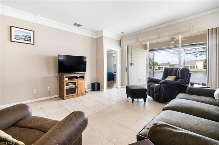 Living room with ornamental molding, ceiling fan, and light tile patterned floors