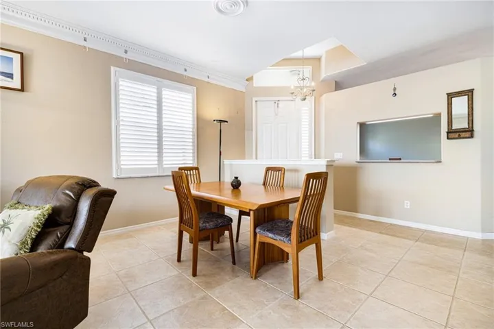 Dining room with an inviting chandelier, ornamental molding, and light tile patterned floors