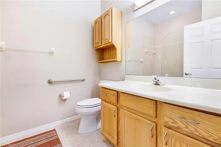 Bathroom with toilet, vanity, a tile shower, and tile patterned flooring