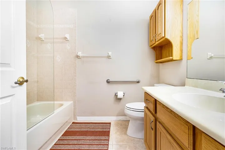 Full bathroom featuring vanity, tiled shower / bath combo, toilet, and tile patterned flooring