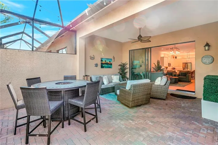 View of patio featuring a lanai, a ceiling fan, and an outdoor living space with a fire pit